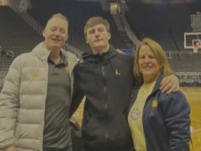 Tyler, Kevin, and Lynn Kolek are posing for the picture together in a basketball court.